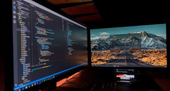 IT technician troubleshooting computer system errors and data recovery on a dual monitor workstation